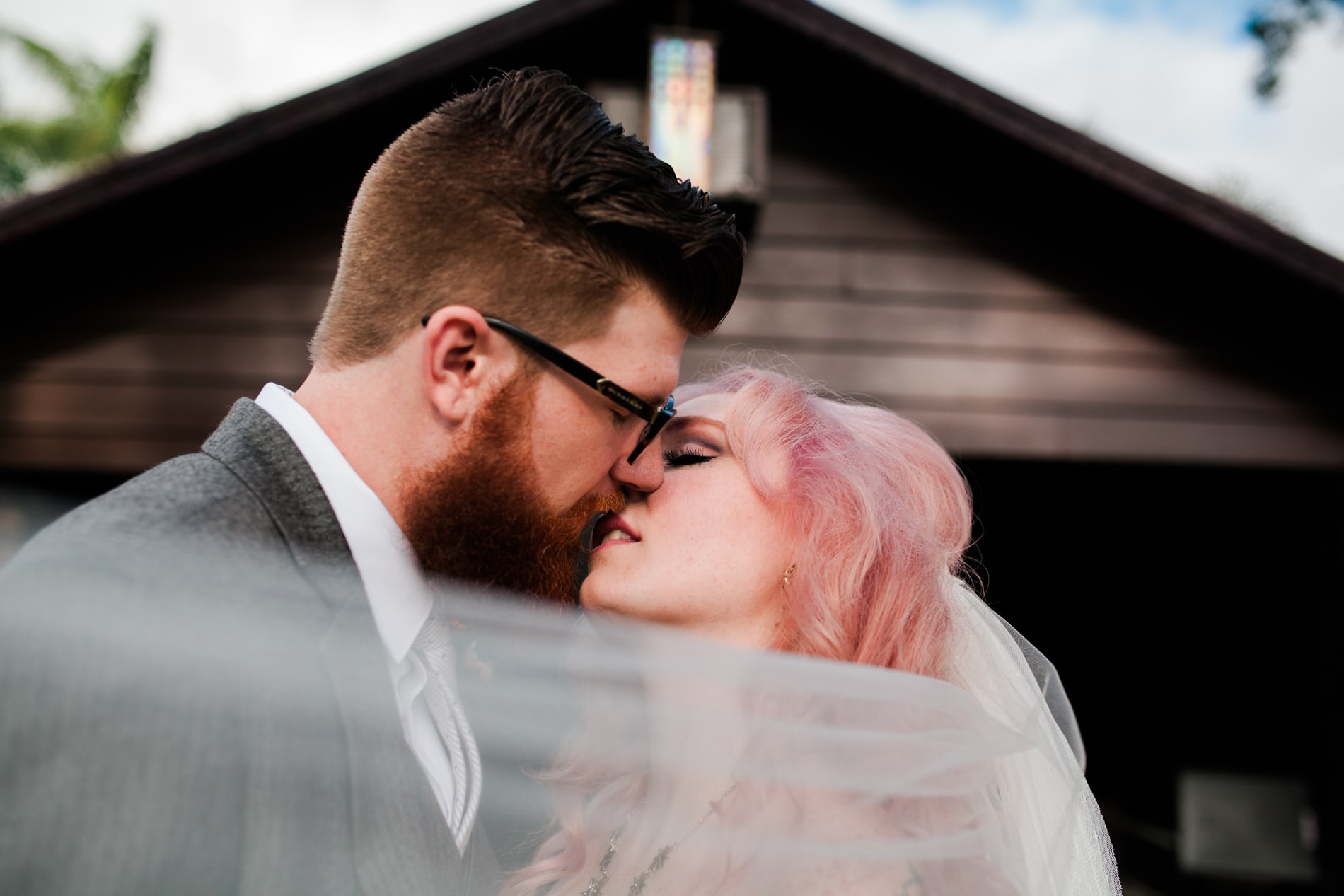Wedding Photographer, a bride and groom lean into kiss before a barn